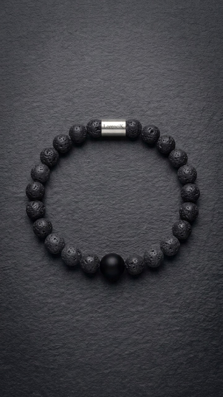 Schwarzes Lavastein-Perlenarmband mit Edelstahlverschluss auf dunklem Schiefer