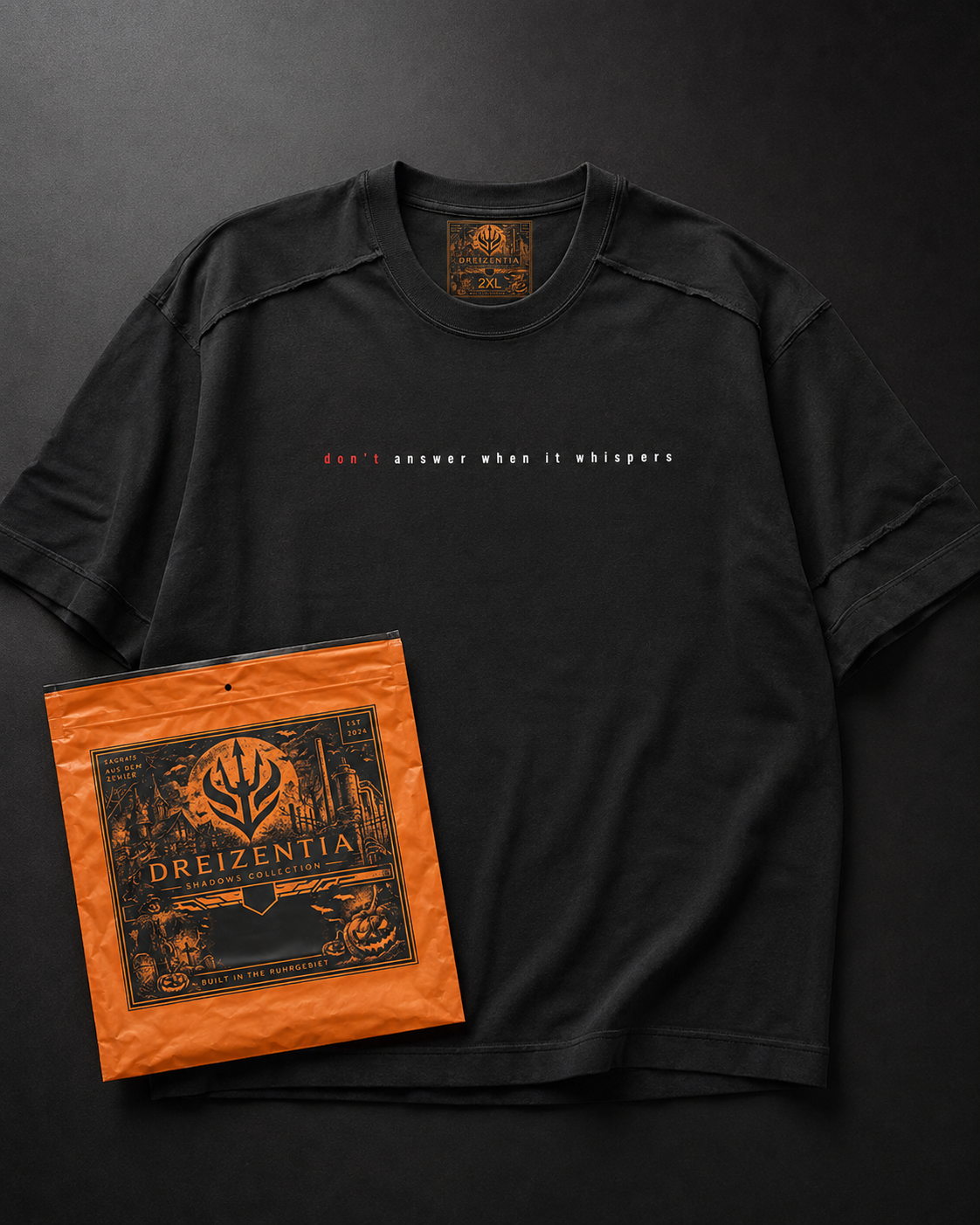 Schwarzes Dreizentia Shadows T-Shirt mit Frontprint und orangefarbener Verpackung als Flatlay