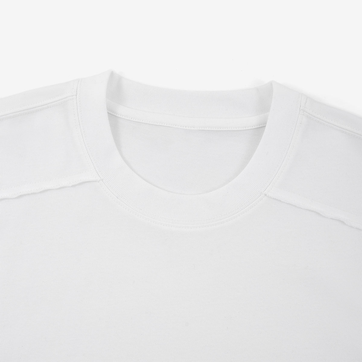Detail der weißen Shirtbasis: gerippter Rundhalsausschnitt, eingefasste Nackennaht und offene Schulternähte.