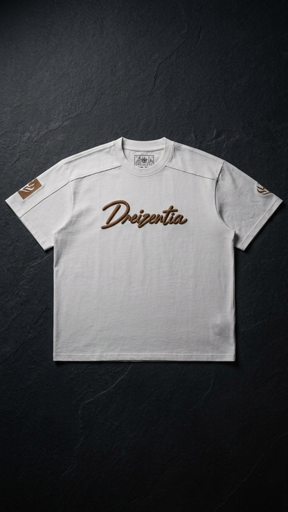 Weißes DREIZENTIA REVIER ROYAL Cognac T-Shirt mit Brustschriftzug und Ärmelmotiven auf dunklem Schiefer.