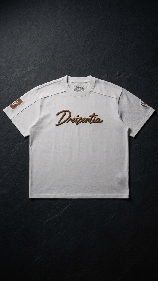 Weißes DREIZENTIA REVIER ROYAL Cognac T-Shirt mit Brustschriftzug und Ärmelmotiven auf dunklem Schiefer.