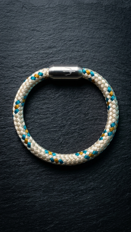 Beige braun blaues geflochtenes Armband mit silberfarbenem Dreizack Verschluss als zweite Produktansicht auf dunklem Schiefer.
