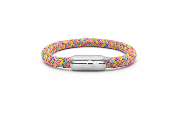 “Geflochtenes Armband in sanften Pastellfarben mit einem Edelstahl-Magnetverschluss, verziert durch ein eingraviertes Dreizack-Symbol. Verspieltes und frisches Design, inspiriert von Leichtigkeit und Farbe.”