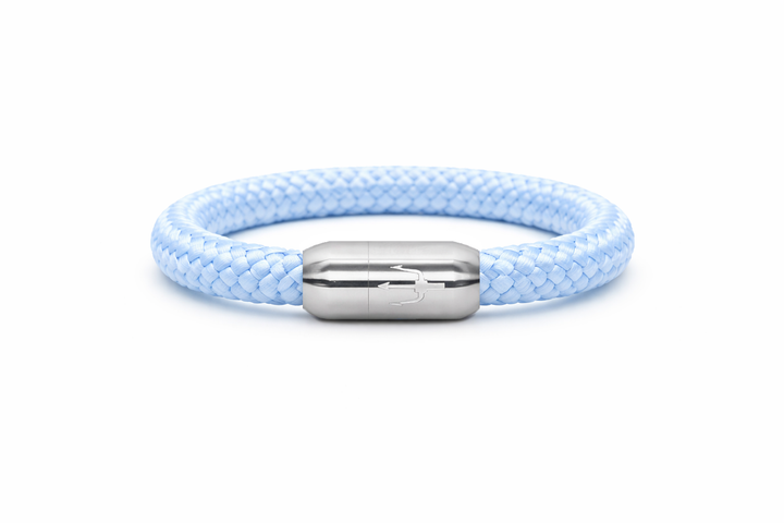 “Zartes, maritimes Armband aus hellblauem, geflochtenem Segeltau mit einem Edelstahl-Magnetverschluss, verziert mit einem eingravierten Dreizack-Symbol. Minimalistisches und stilvolles Design für einen eleganten Look.”