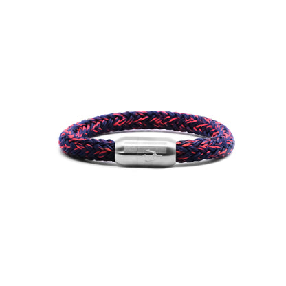“Geflochtenes Armband in Dunkelblau mit feinen roten Akzenten und einem Edelstahl-Magnetverschluss, verziert durch ein eingraviertes Dreizack-Symbol. Stilvolles und dynamisches Design, inspiriert von der Energie der Nacht.”