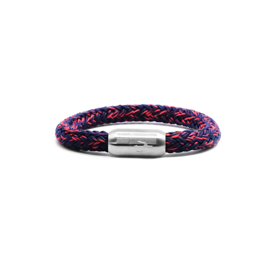 “Geflochtenes Armband in Dunkelblau mit feinen roten Akzenten und einem Edelstahl-Magnetverschluss, verziert durch ein eingraviertes Dreizack-Symbol. Stilvolles und dynamisches Design, inspiriert von der Energie der Nacht.”