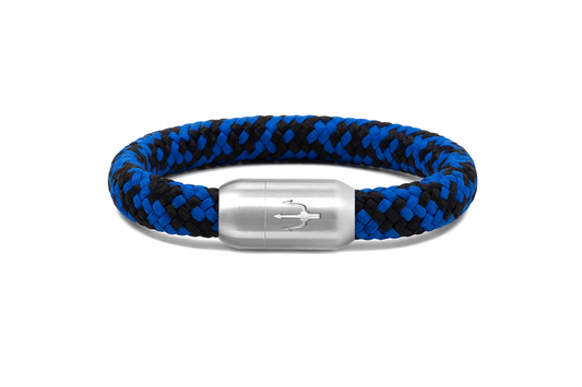 “Geflochtenes Armband in Blau und Schwarz mit einem Edelstahl-Magnetverschluss, verziert durch ein eingraviertes Dreizack-Symbol. Kraftvolles maritimes Design, das Tiefe und Dynamik vereint.”