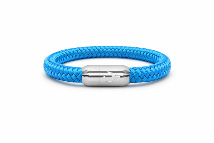 "Hellblaues Armband aus geflochtenem Segeltau mit einem Edelstahl-Magnetverschluss, verziert mit einem eingravierten Dreizack-Symbol. Frisches und modernes maritimes Design.”