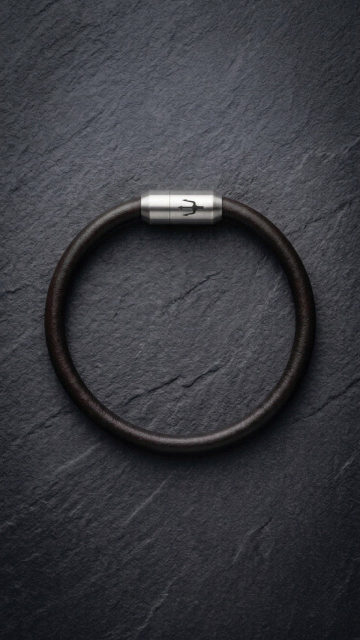 Dunkelbraunes Lederarmband mit Edelstahlverschluss auf dunklem Schiefer
