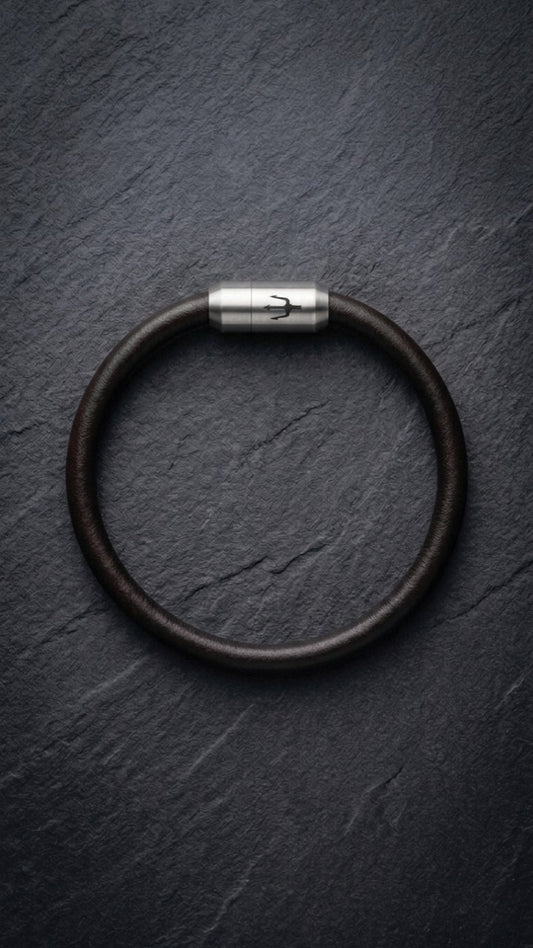 Dunkelbraunes Lederarmband mit Edelstahlverschluss auf dunklem Schiefer