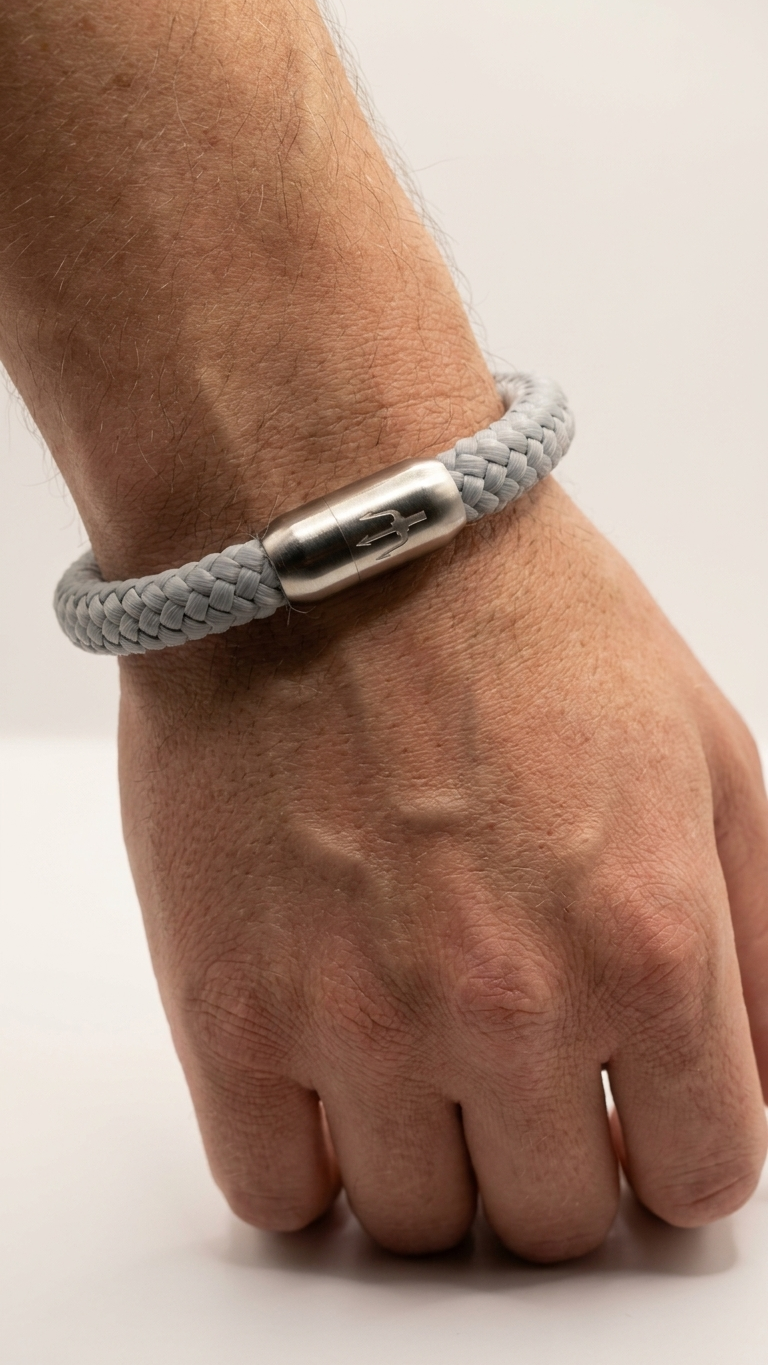 Hellgraues geflochtenes Seilarmband mit Edelstahlverschluss als Detailaufnahme am Handgelenk