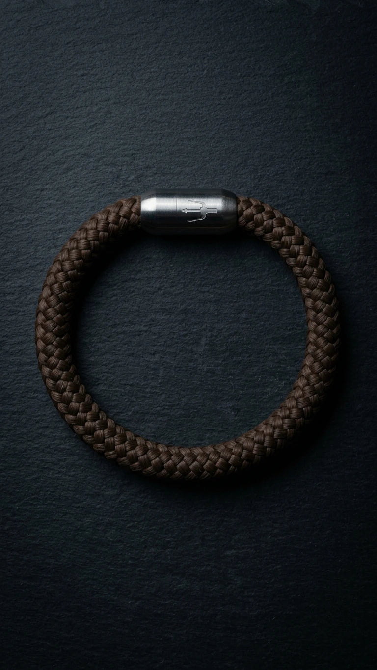 Nautic Force Dark Harbor – dunkelbraunes 8-mm-Segeltauarmband mit gebürstetem Edelstahlverschluss und Dreizack auf dunklem Schiefer