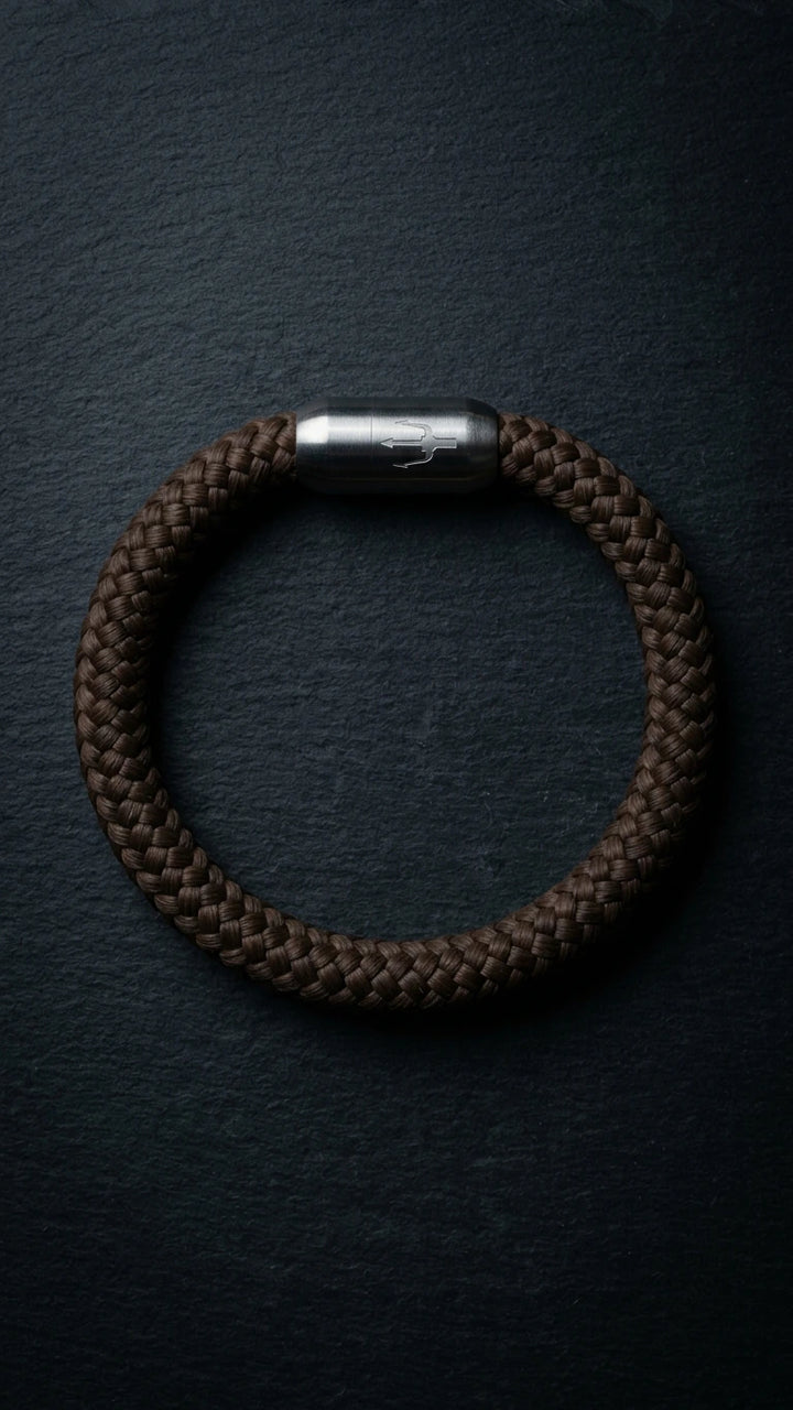 Nautic Force Dark Harbor – dunkelbraunes 8-mm-Segeltauarmband mit gebürstetem Edelstahlverschluss und Dreizack auf dunklem Schiefer