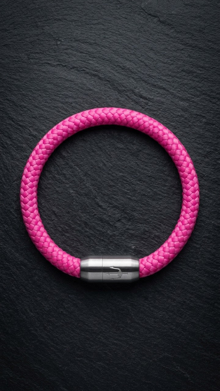 Pinkes geflochtenes Armband mit silberfarbenem Dreizack Verschluss als Produktfoto auf dunklem Schiefer.