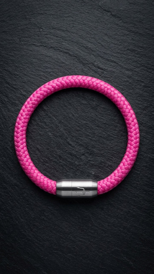 Pinkes geflochtenes Armband mit silberfarbenem Dreizack Verschluss als Produktfoto auf dunklem Schiefer.