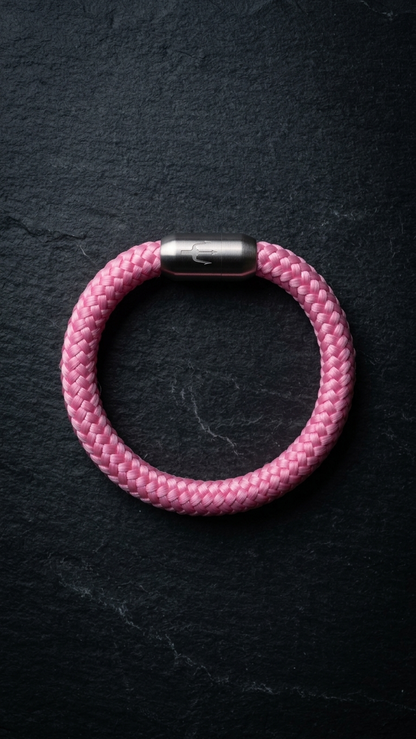 Rosa geflochtenes Seilarmband mit Edelstahlverschluss als Produktfoto auf dunklem Schiefer