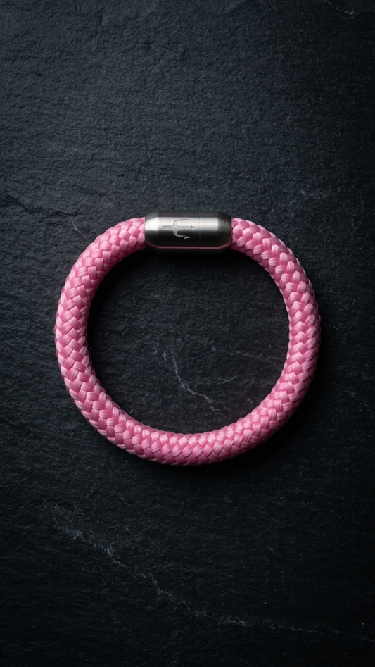 Rosa geflochtenes Seilarmband mit Edelstahlverschluss als Produktfoto auf dunklem Schiefer