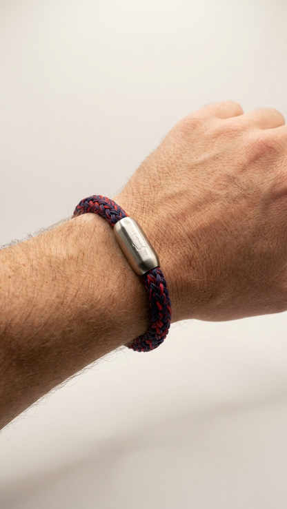 Rot-blaues geflochtenes Seilarmband mit Edelstahlverschluss als Detailaufnahme am Handgelenk