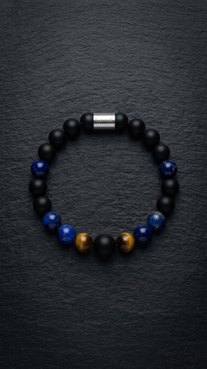 Schwarz-blaues Perlenarmband mit Tigerauge-Akzenten und Edelstahlverschluss auf dunklem Schiefer