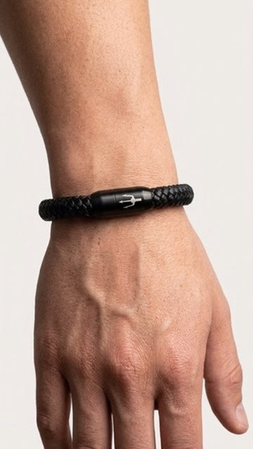 Schwarzes geflochtenes Armband mit dunklem Verschluss am Handgelenk