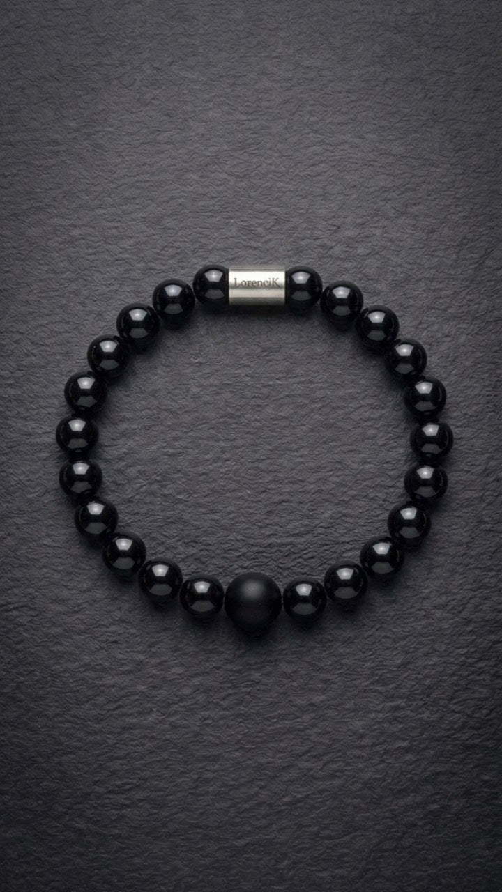 Schwarzes glänzendes Perlenarmband mit Edelstahlverschluss auf dunklem Schiefer