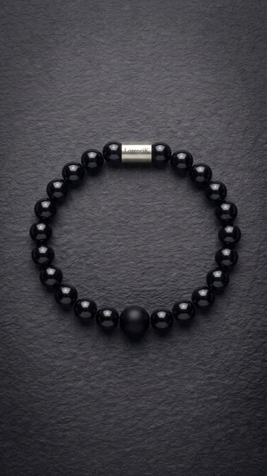 Schwarzes glänzendes Perlenarmband mit Edelstahlverschluss auf dunklem Schiefer
