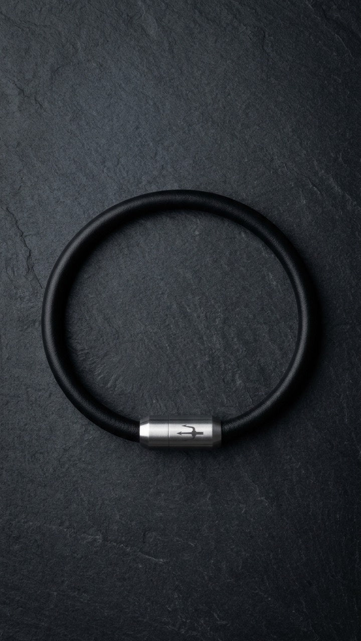 Schwarzes glattes Lederarmband mit silberfarbenem Dreizack Verschluss auf dunklem Schiefer.