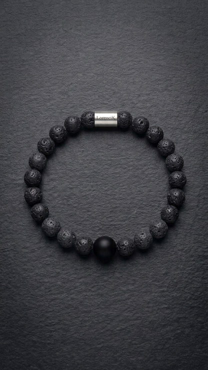 Schwarzes Lavastein-Perlenarmband mit Edelstahlverschluss auf dunklem Schiefer