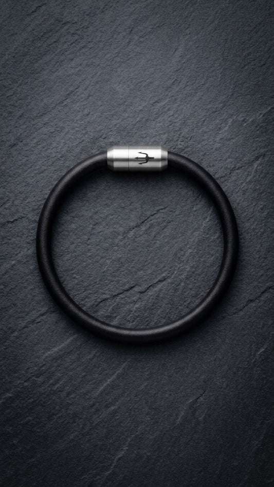 Schwarzes Lederarmband mit Edelstahlverschluss auf dunklem Schiefer