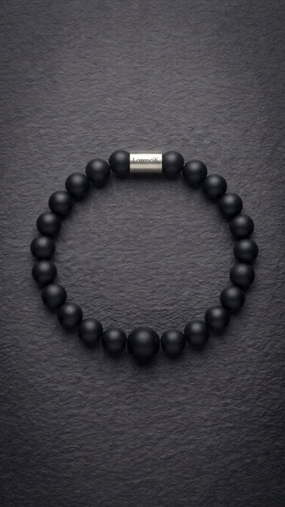 Schwarzes mattes Perlenarmband mit Edelstahlverschluss auf dunklem Schiefer