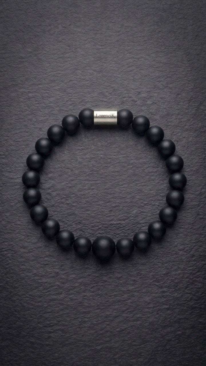Schwarzes mattes Perlenarmband mit Edelstahlverschluss auf dunklem Schiefer