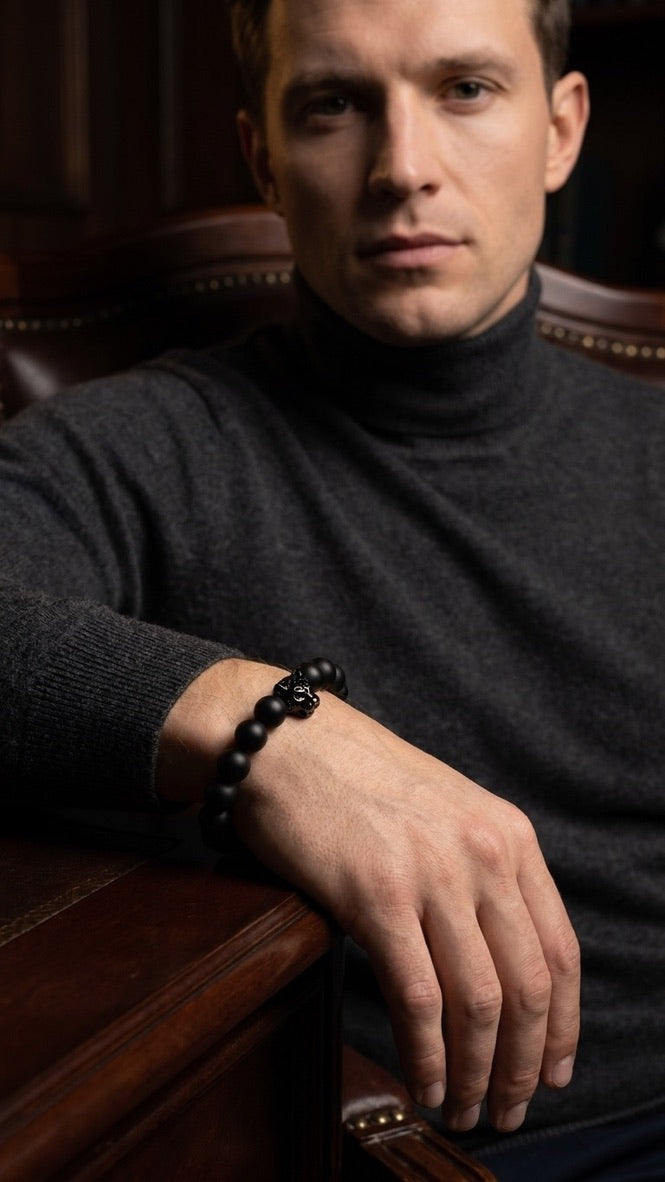 Schwarzes Perlenarmband mit Totenkopf-Detail am Handgelenk im Ledersessel