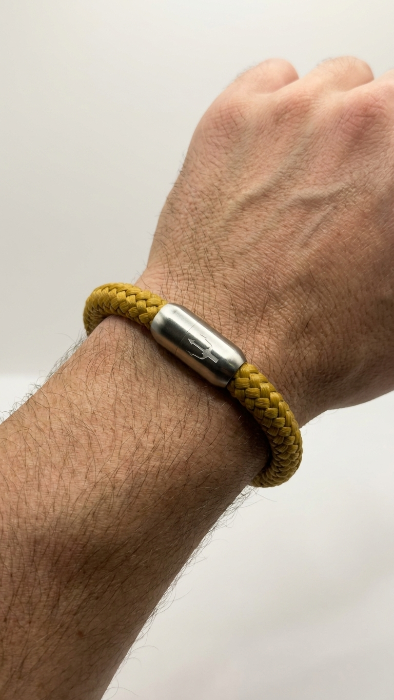 Senfgelbes geflochtenes Seilarmband mit Edelstahlverschluss als Detailaufnahme am Handgelenk