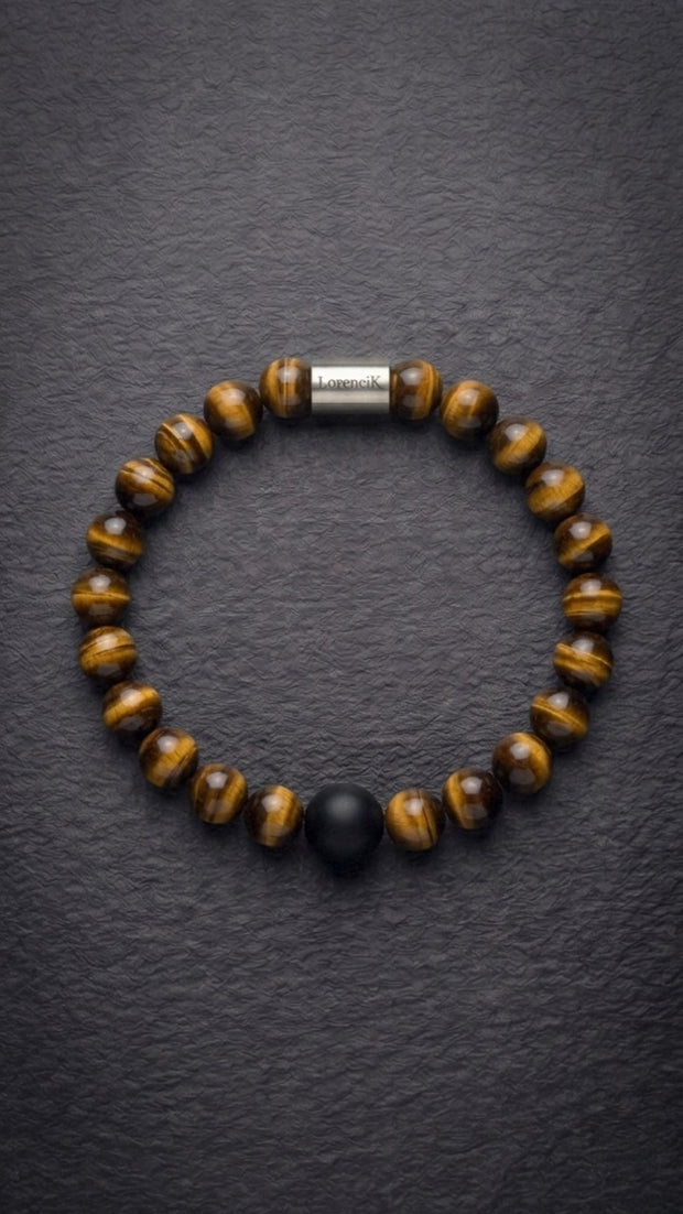 Tigerauge-Perlenarmband mit Edelstahlverschluss und schwarzer Akzentperle auf dunklem Schiefer