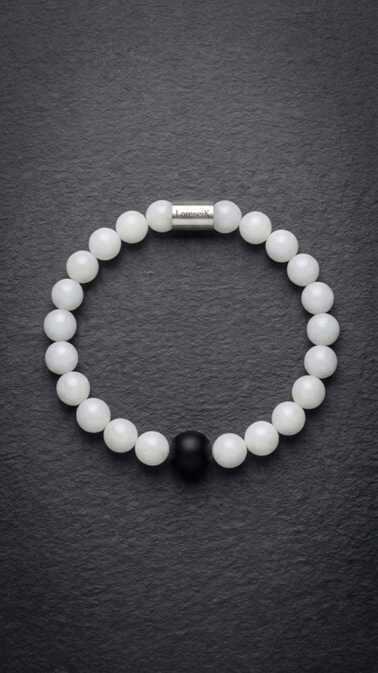 Weißes Perlenarmband mit Edelstahlverschluss und schwarzer Akzentperle auf dunklem Schiefer